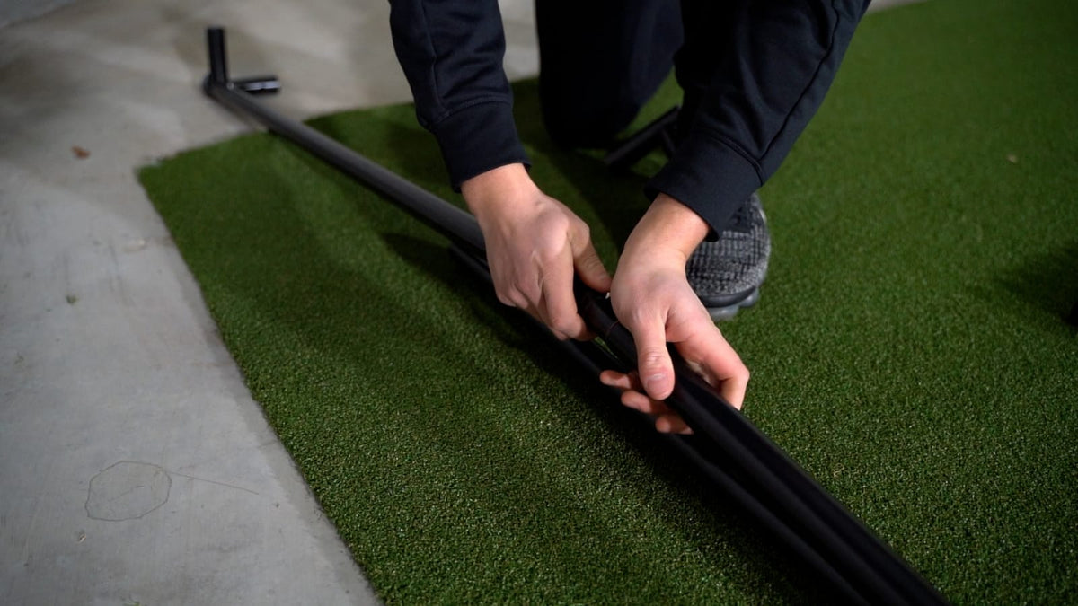 SimBox Golf Simulator Enclosure with black metal frame components being assembled by hand