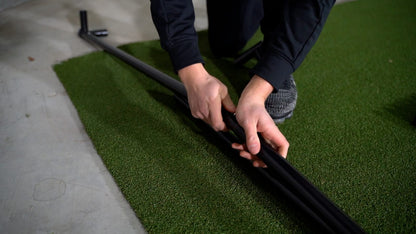 SimBox Golf Simulator Enclosure with black metal frame components being assembled by hand