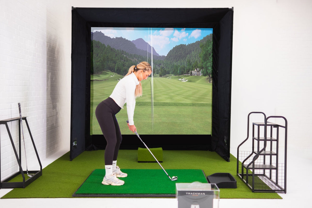 SimBox Golf Simulator Enclosure with a black frame, impact screen displaying a golf course, and green hitting mat