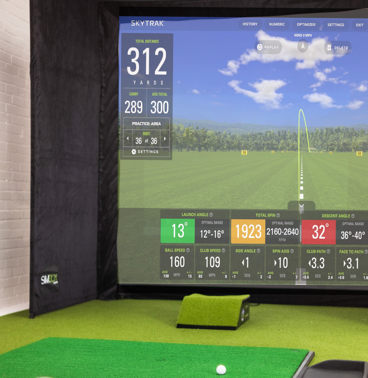 SimBox Golf Simulator Enclosure with black fabric side panels, an HD golf screen, and green turf hitting mat