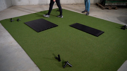 SimBox Golf Simulator Enclosure with green artificial turf flooring and black ribbed panels and mounting brackets